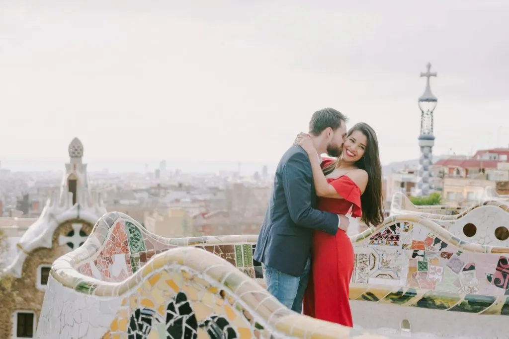 Couple sitting on the mosaic bench overlooking Barcelona at Park Güell